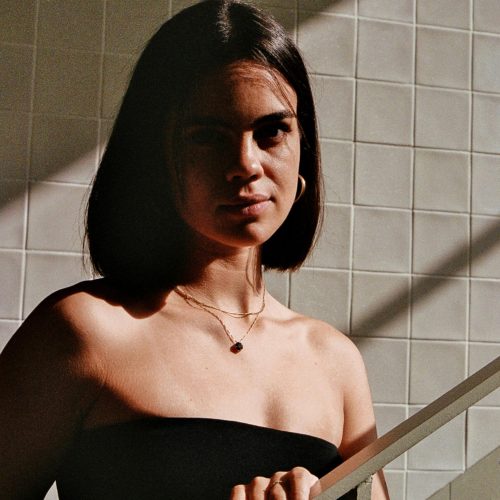 Stylish woman with short hair posing indoors with dramatic lighting and shadows.